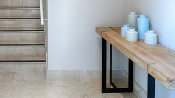 Un banc en bois doté d’une structure en métal noir, avec un mur blanc en arrière-plan.