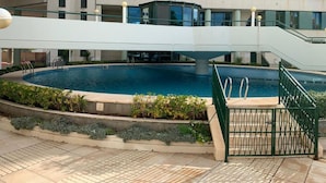 A swimming pool with a bridge and stairs, surrounded by a landscaped area with plants.