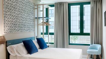A modern hotel room with a large bed, a chair, and a window with curtains.