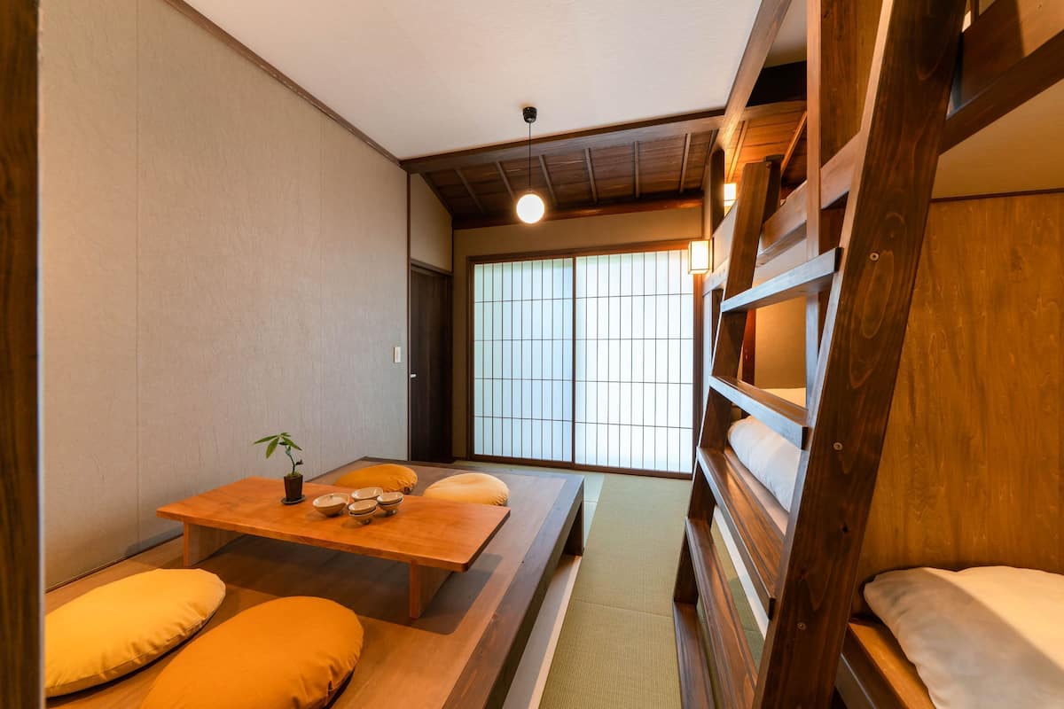 A traditional Japanese room with tatami flooring, a low wooden table with cushions, and a sliding shoji screen door.