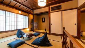 A tatami mat room with a low table, cushions, and a sliding door. - Saik (Kanazawa)