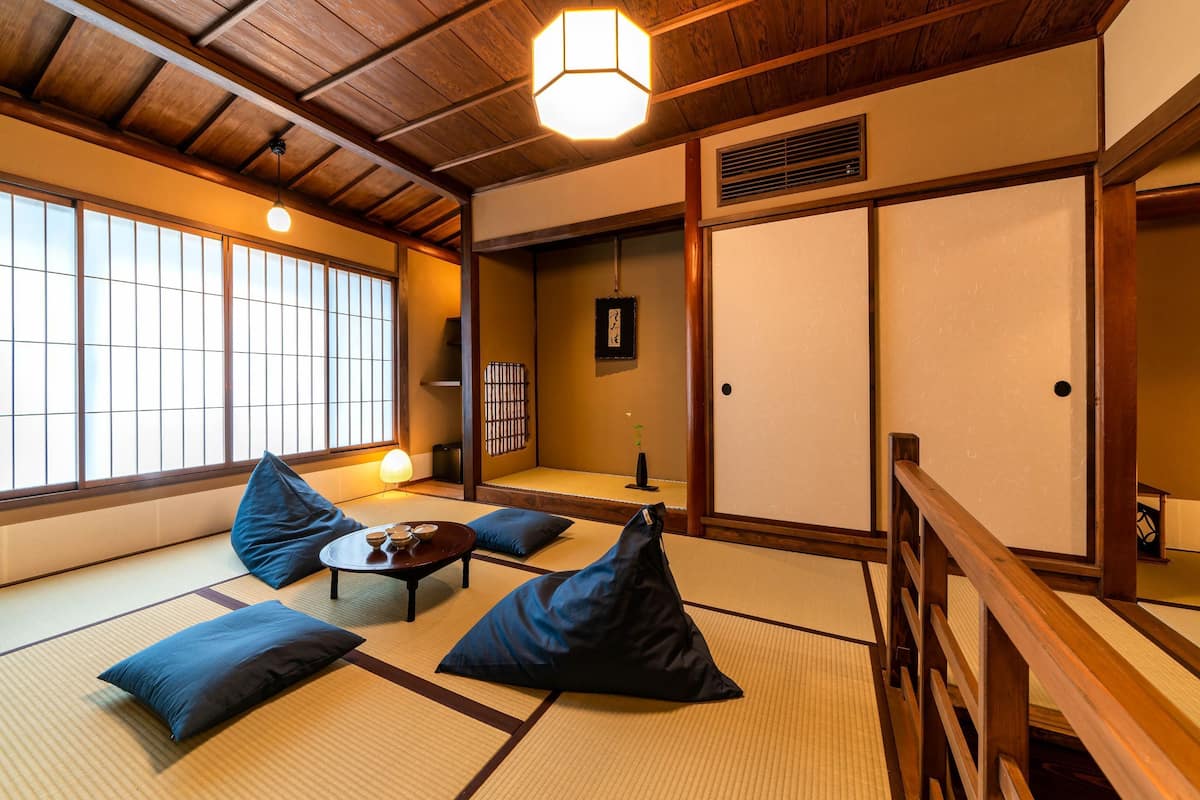 A tatami mat room with a low table, cushions, and a sliding door.