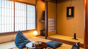 A traditional Japanese room with tatami flooring, low wooden beams, a shoji screen, and a hanging light fixture. - Saik (Kanazawa)