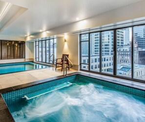 Una piscina interior moderna con amplias vistas de la ciudad a través de grandes ventanales.