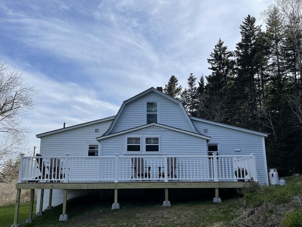Une maison à deux étages avec un porche à l’avant et une terrasse.