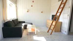 A living room with a sofa, a coffee table, a TV stand, and a wooden ladder. - Quisten (Nes)