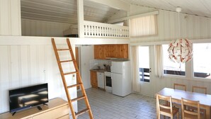 A compact kitchen with wooden cabinets, a refrigerator, and a dining area with a table and chairs. - Quisten (Nes)