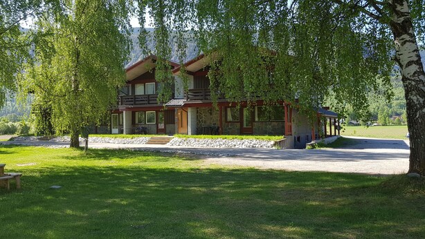A two-story lodge with a stone facade, a balcony, and a stone pathway leading to the entrance. - Quisten (Nes)