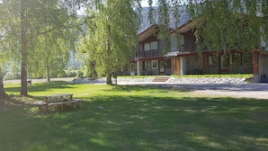 A lodge with a stone facade, a wooden deck, and a picnic table in a lush, green setting. - Quisten (Nes)