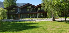 A two-story lodge with a stone facade, large windows, and a balcony. - Quisten (Nes)