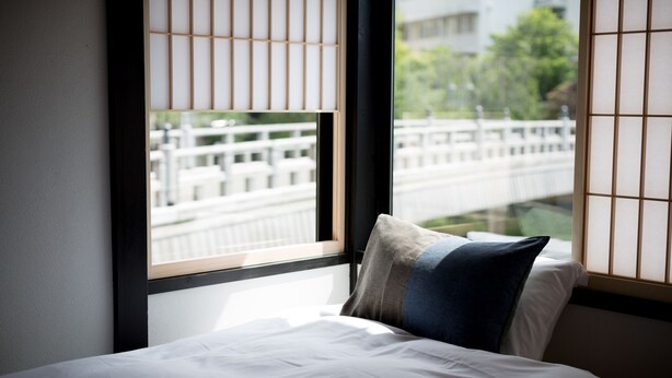 A hotel room with a bed, a window with a view of a bridge, and a traditional Japanese shoji screen. - Higashiyama Aritsuki (Kanazawa)