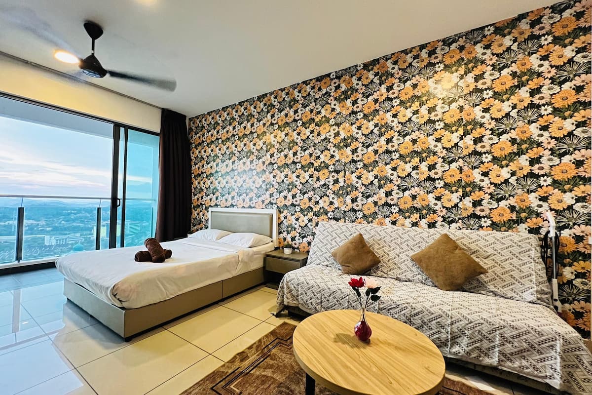 Habitación de hotel con una cama grande, un sofá, una mesita y vistas a la ciudad.