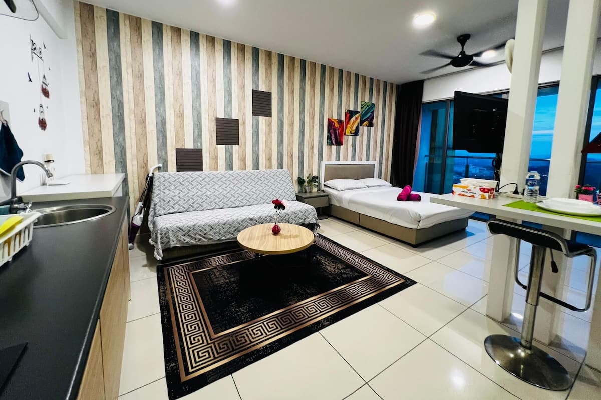 Una sala de estar moderna con sofá, una mesa de centro, un comedor con una silla, una cocina con fregadero y vistas a la ciudad.