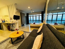 Una sala de estar moderna con un sofá, una mesa de centro, un televisor y un ventanal que ofrece vistas a la ciudad.