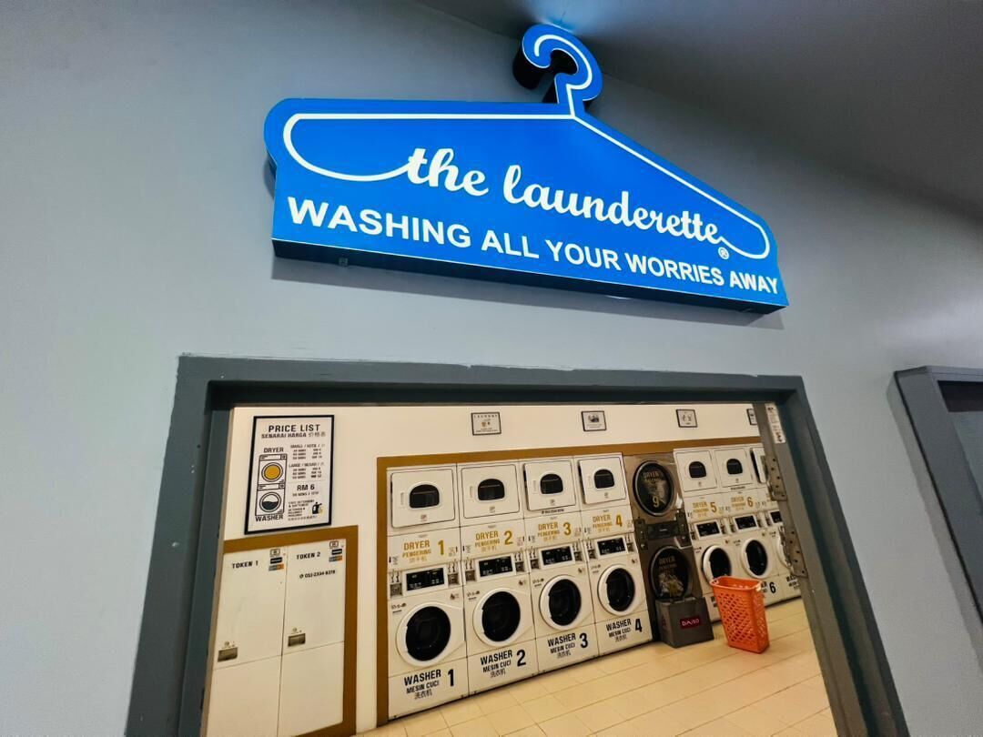 A laundromat with a sign reading 'the laundrette. WASHING ALL YOUR WORRIES AWAY.'