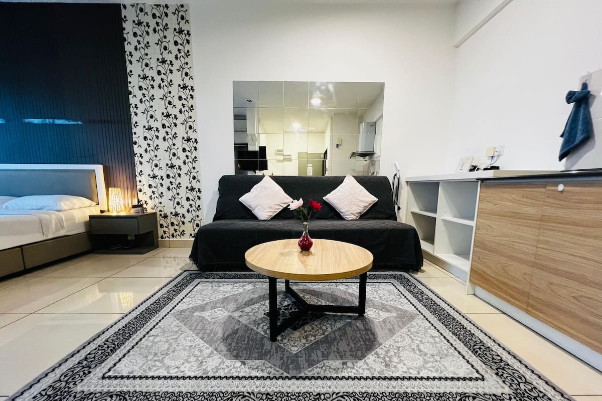 Una sala de estar moderna con un sofá, una mesa de centro, una alfombra estampada y vistas a la cocina.
