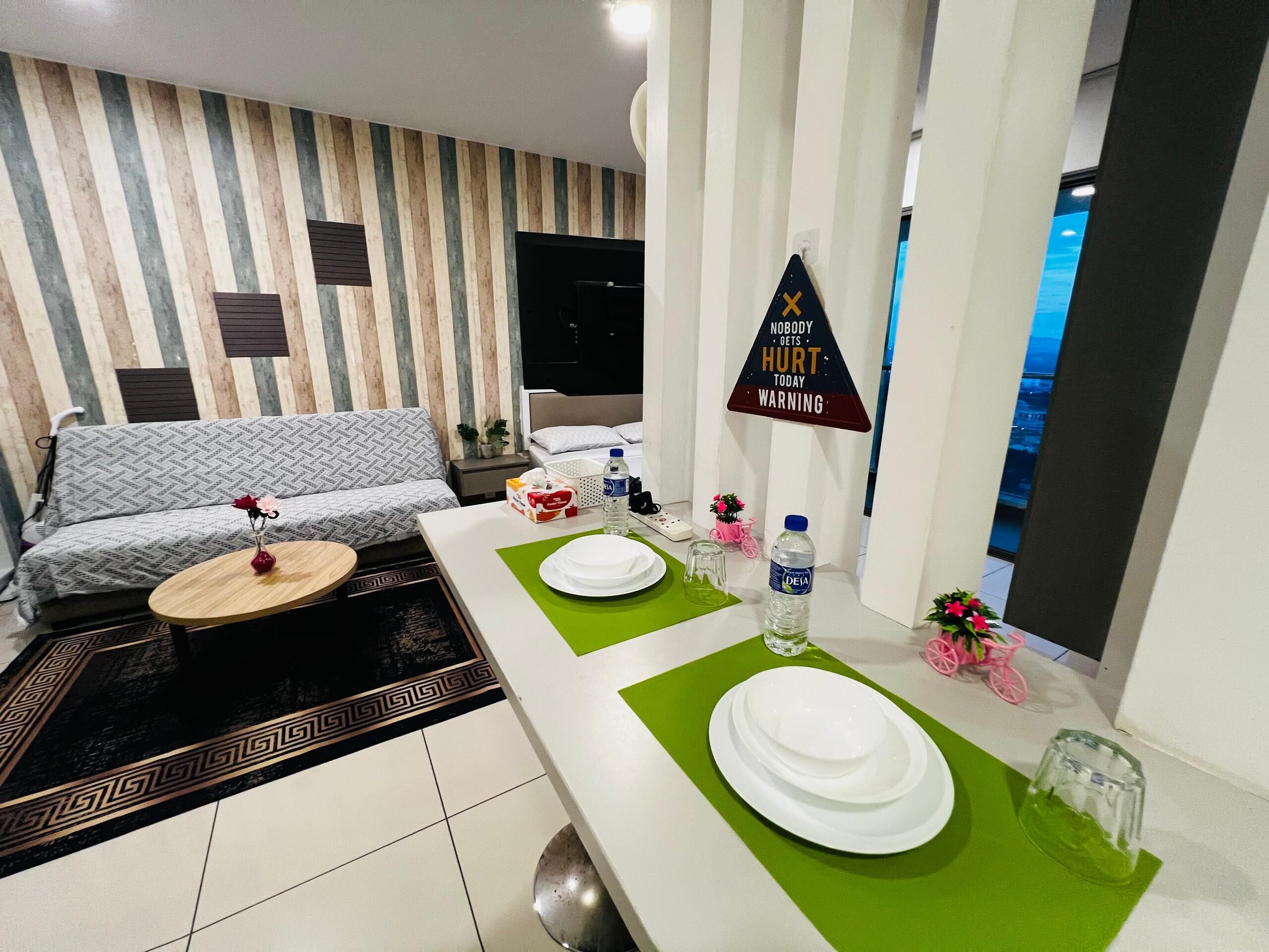 A modern living room with a sofa, a coffee table, and a dining area set with plates and a bottle.