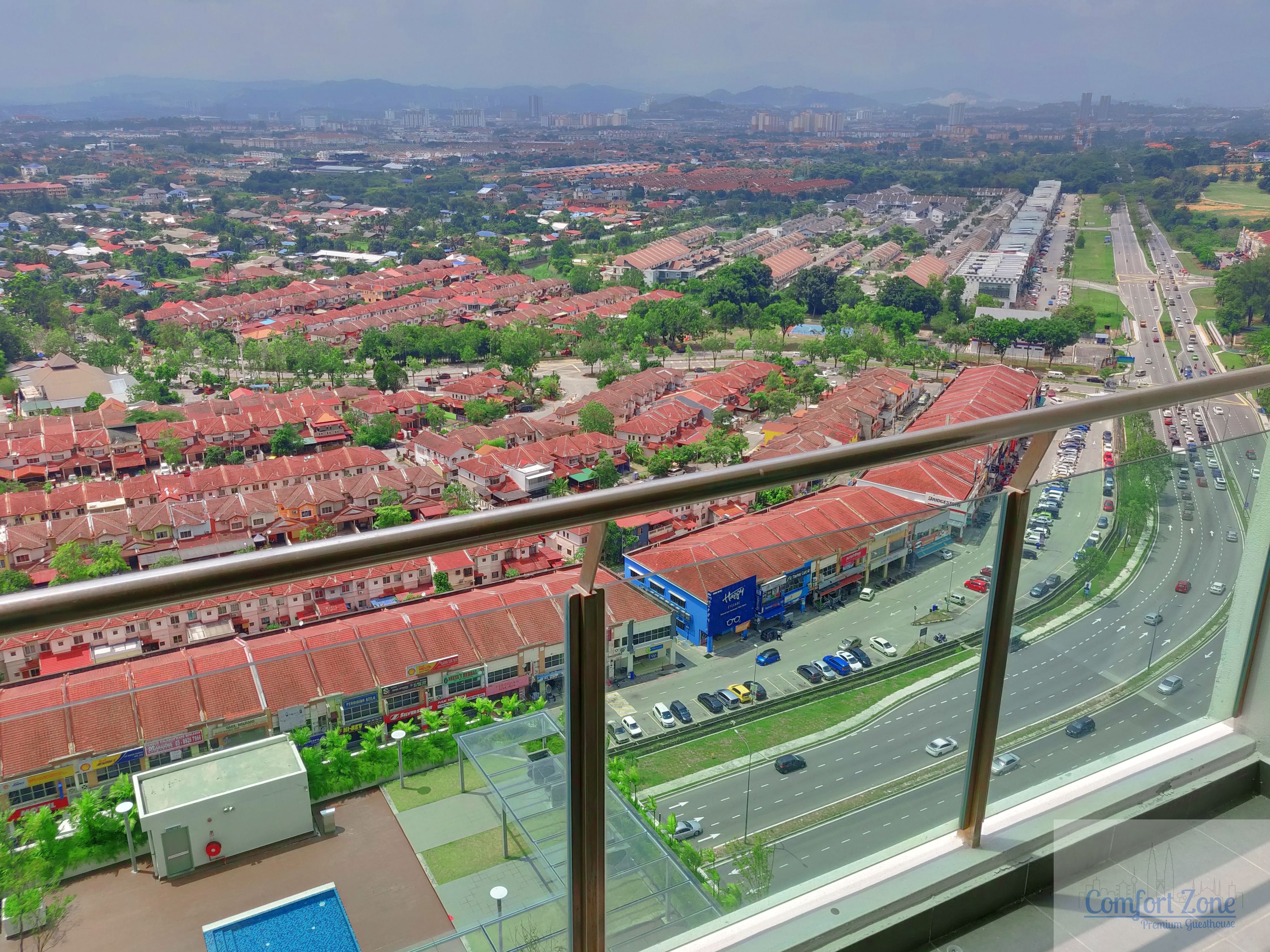 A high-rise hotel with a view of a cityscape, featuring a parking area and a road with vehicles.