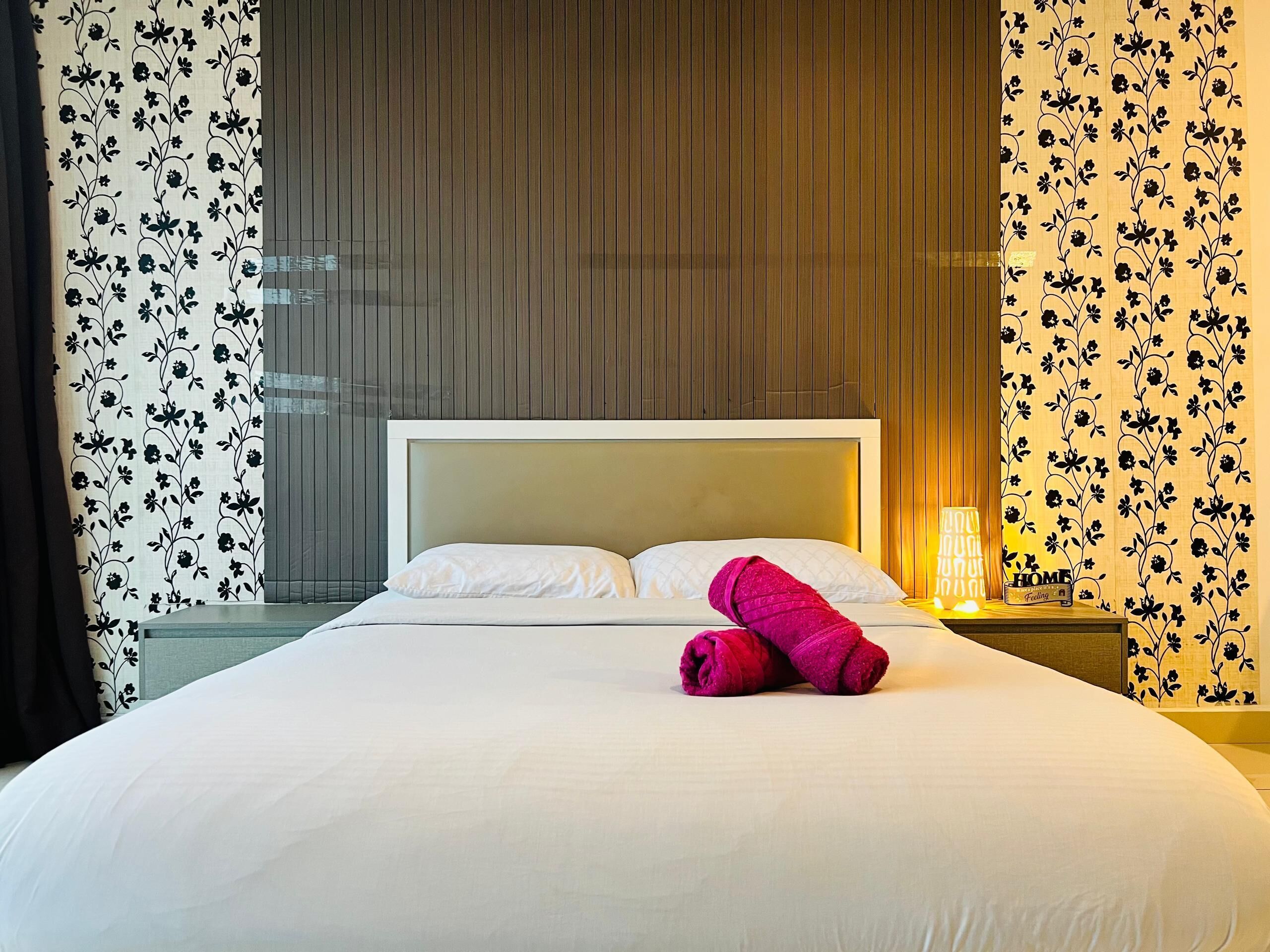 Ein Hotelzimmer mit einem Bett, einem Nachttisch mit Lampe und blumengemusterten Vorhängen.