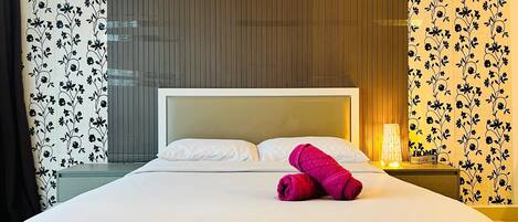 Ein Hotelzimmer mit einem Bett, einem Nachttisch mit Lampe und blumengemusterten Vorhängen.