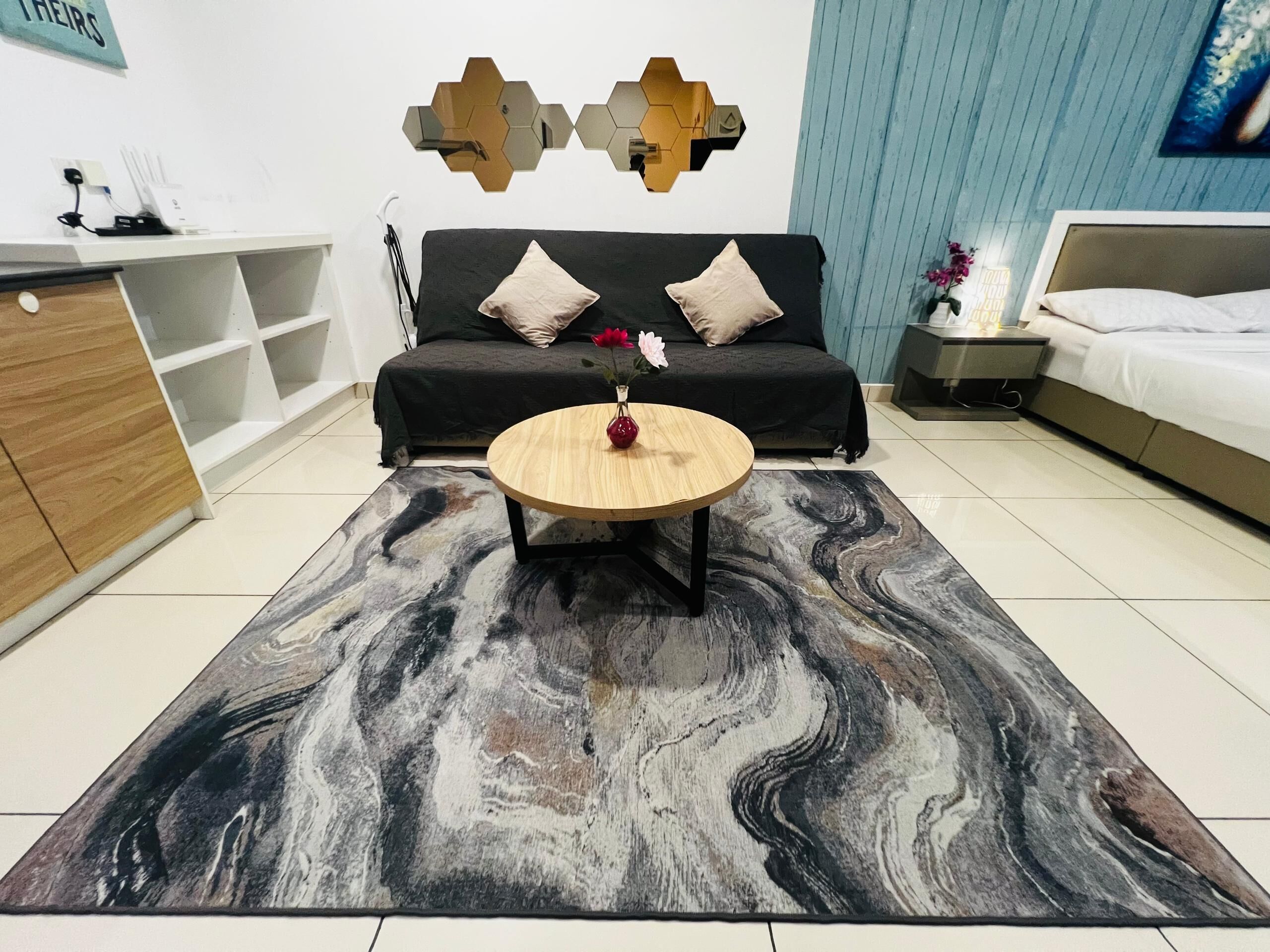 A modern living room with a sofa, a coffee table, a TV, and a decorative wall piece.