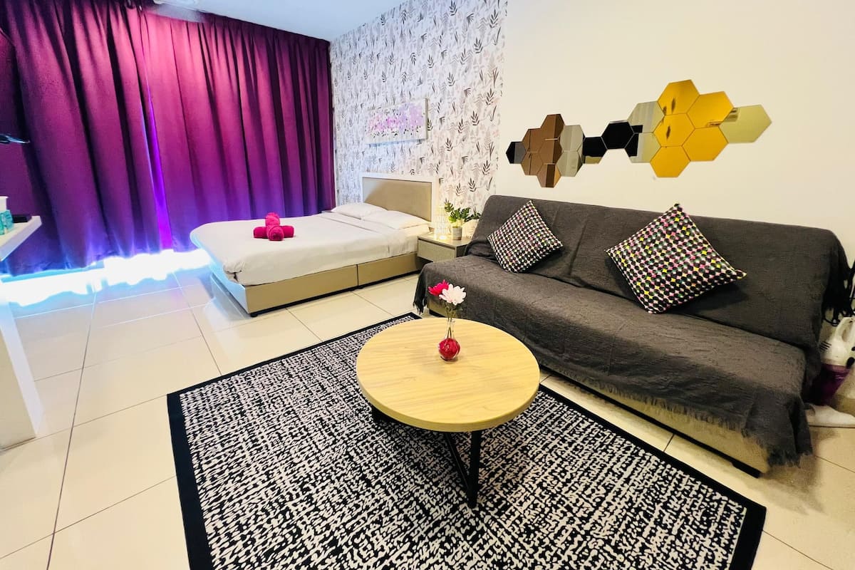 Un dormitorio moderno con una cama, un sofá, una mesita de centro y una alfombra estampada.