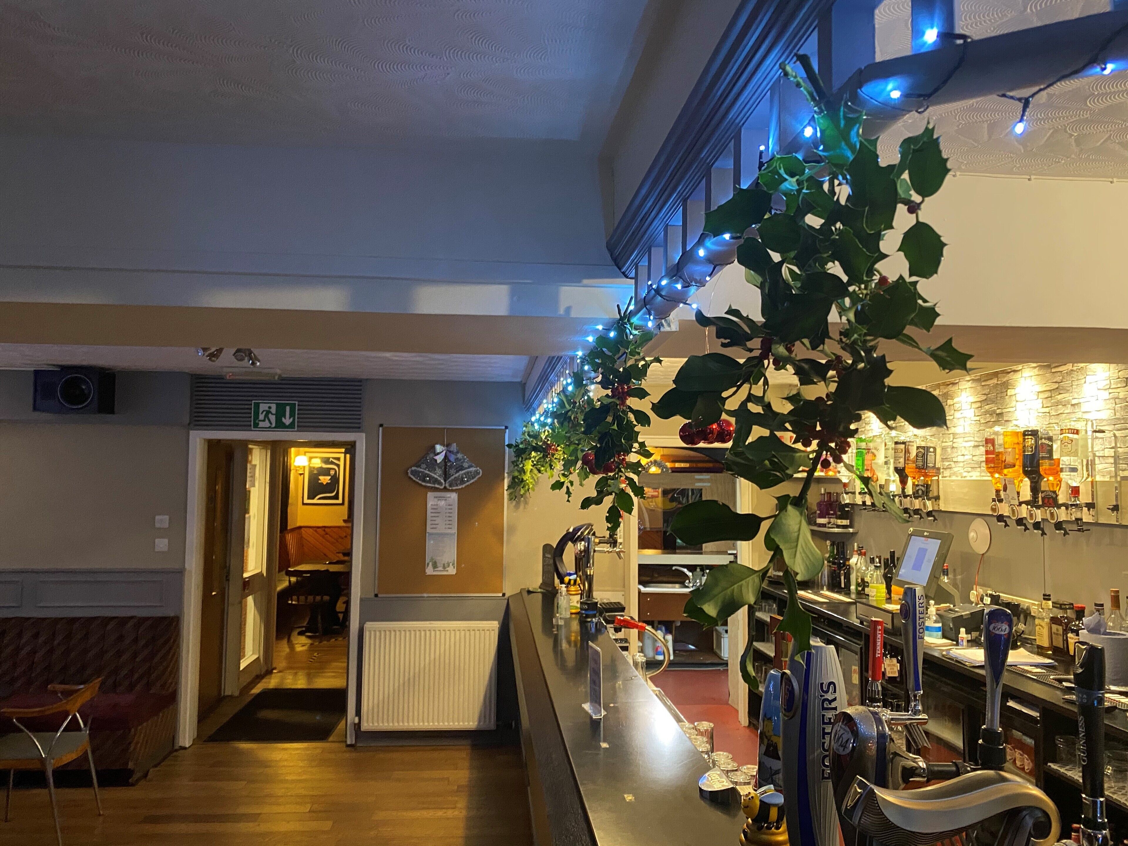 A bar area with multiple taps, a menu board, and a Christmas decoration.