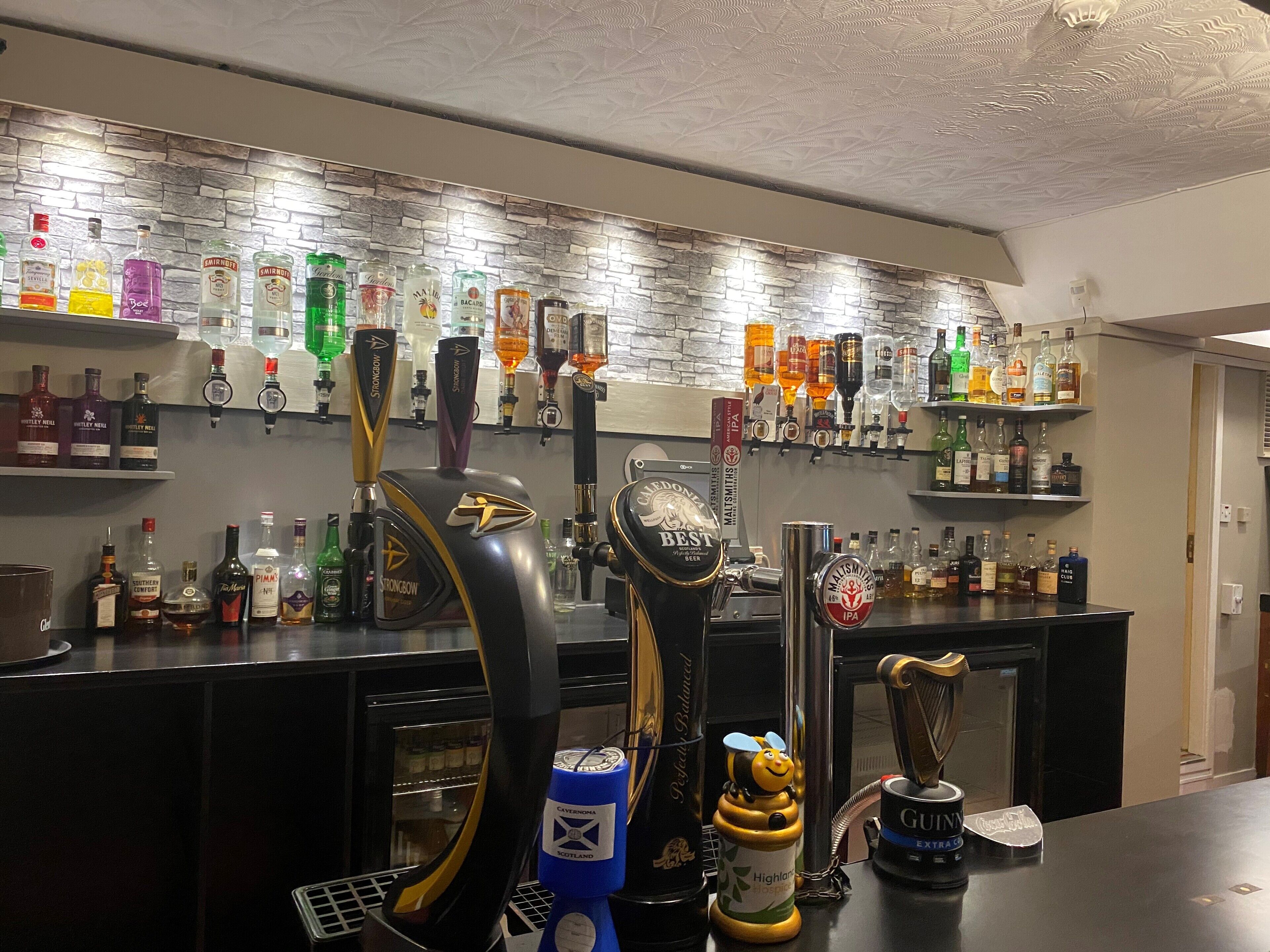 A bar area with multiple beer taps, a variety of liquor bottles, and a decorative honey dipper.