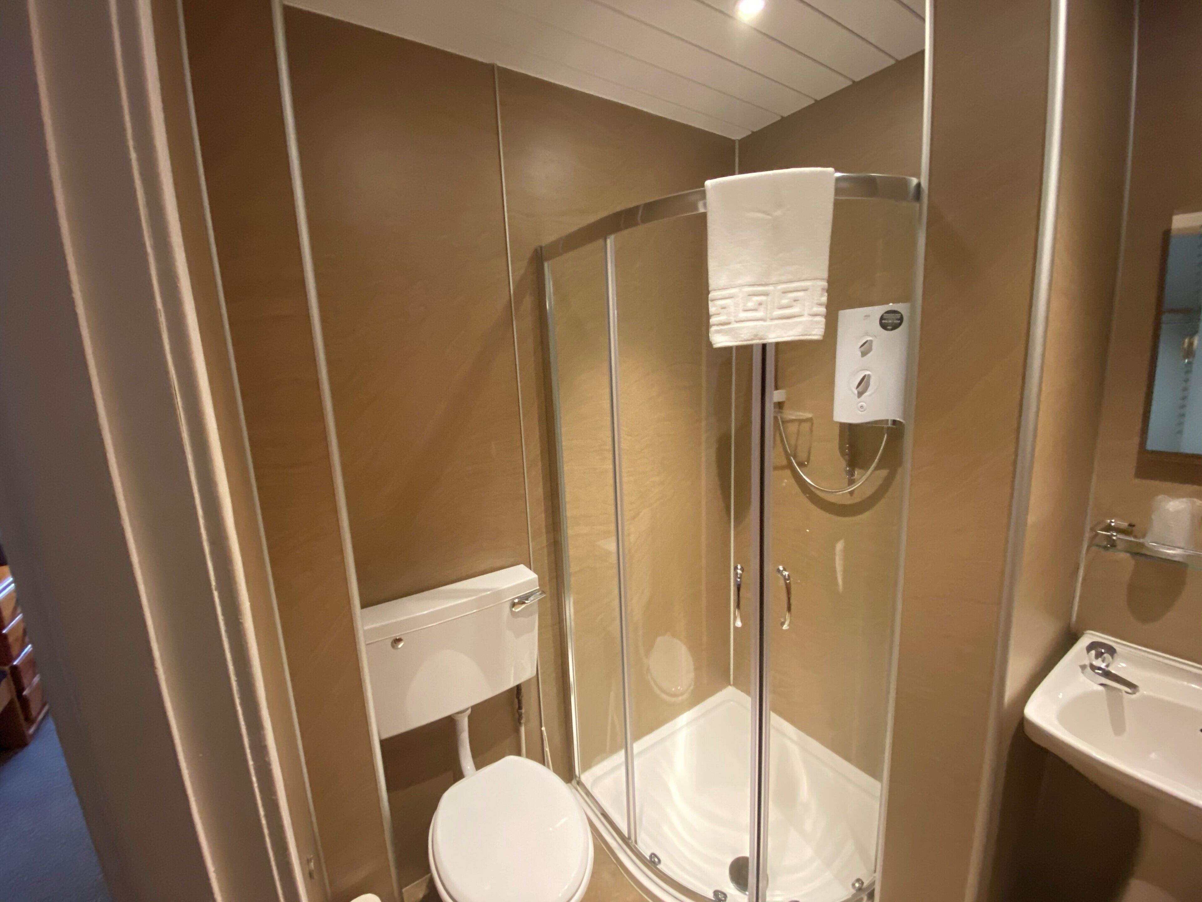 Une salle de bain moderne avec une douche à parois de verre, des toilettes blanches et un lavabo.