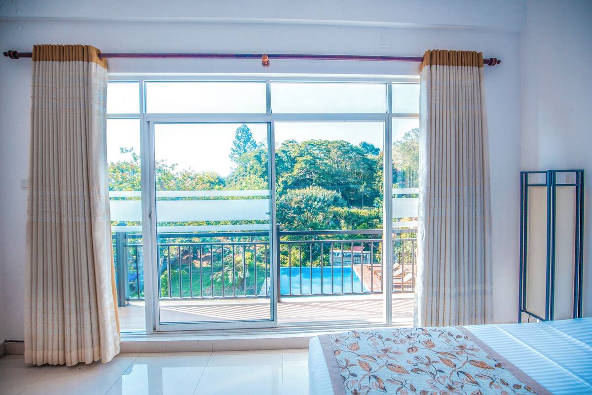 A bedroom with a large sliding glass door leading to a balcony with a pool view.