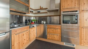 Uma cozinha moderna com eletrodomésticos de aço inoxidável, armários de madeira e forno embutido.