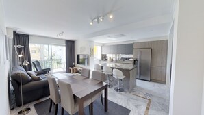 Un appartement moderne comprenant un coin repas, un canapé, une télévision, une cuisine et un balcon.