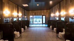 A public restroom with wooden paneling, individual stalls, and a large window providing a view of trees. - Hotel Route Inn Osaka Takaishi Hagoromo Ekimae (Takaishi)