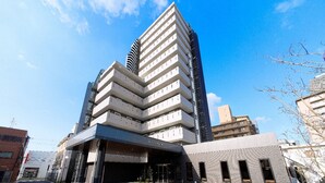 A modern multi-story hotel with a distinctive zigzag facade, a covered entrance, and a parking lot. - Hotel Route Inn Osaka Takaishi Hagoromo Ekimae (Takaishi)