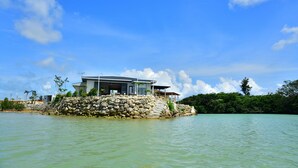 Ein modernes Haus auf einer kleinen Insel unter blauem Himmel.