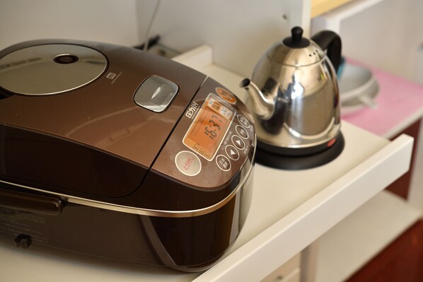 A kitchen with a coffee maker and a rice cooker on the counter.