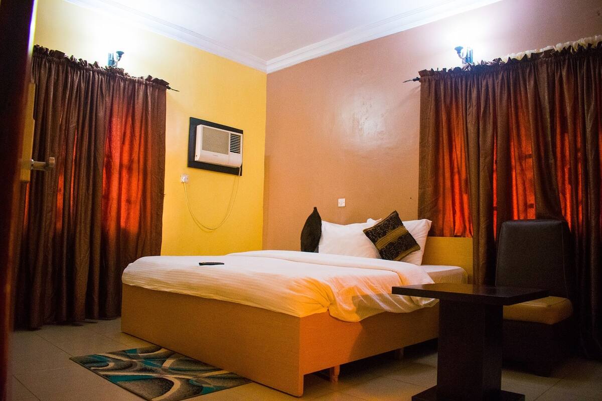 A hotel room with a bed, a chair, and a desk.