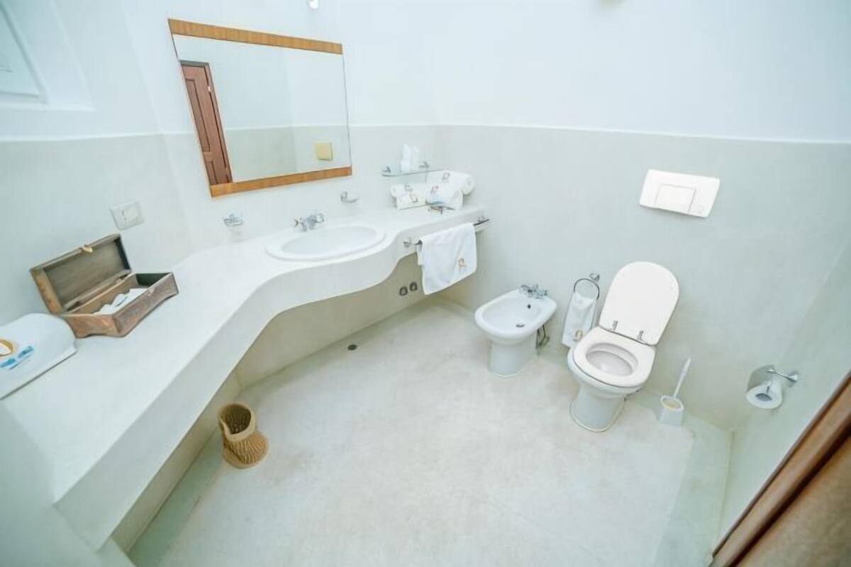 A bathroom with a sink, bidet, toilet, and a mirror.