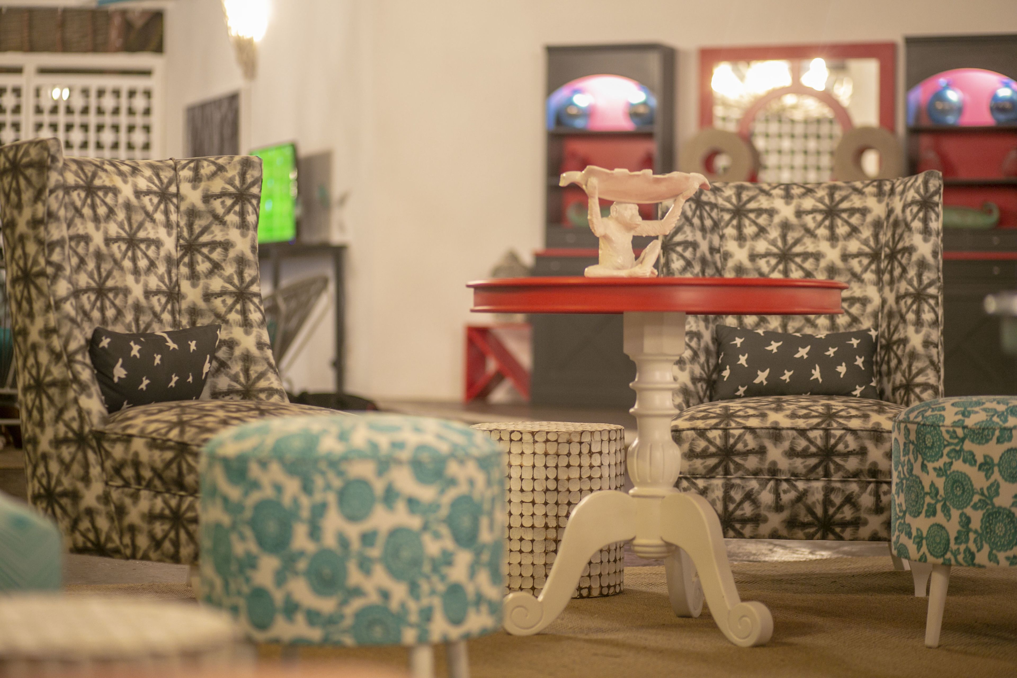 A room with patterned armchairs, a small table with a red top, and a decorative item on the table.