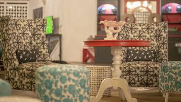 A room with patterned armchairs, a small table with a red top, and a decorative item on the table.