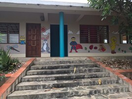 Un edificio con una escalera que lleva a una puerta, decorado con personajes de caricatura y un pilar azul.