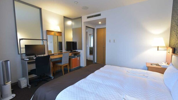 A hotel room with a bed, desk, chair, television, and a mirror. - Blossom Hotel Hirosaki (Hirosaki)