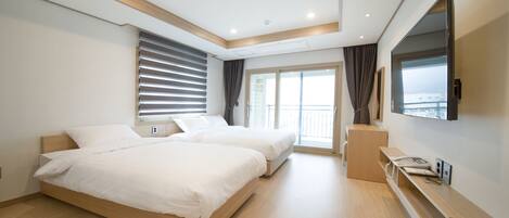 A modern hotel room with two beds, a large window with blinds, a flat-screen TV, and a wooden bench.