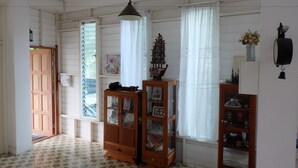 A room with a wooden door, a patterned floor, a hanging light fixture, and a cabinet with glass doors. - Villa Sittiprapa (Nakhon Ratchasima)