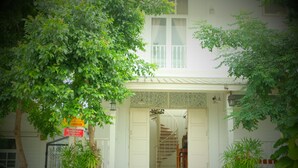 A two-story building with a staircase leading to the entrance, surrounded by greenery. - Villa Sittiprapa (Nakhon Ratchasima)