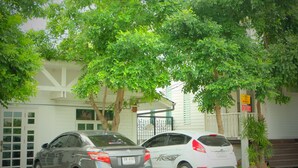 Two cars parked in front of a building with a white facade and a gated entrance. - Villa Sittiprapa (Nakhon Ratchasima)
