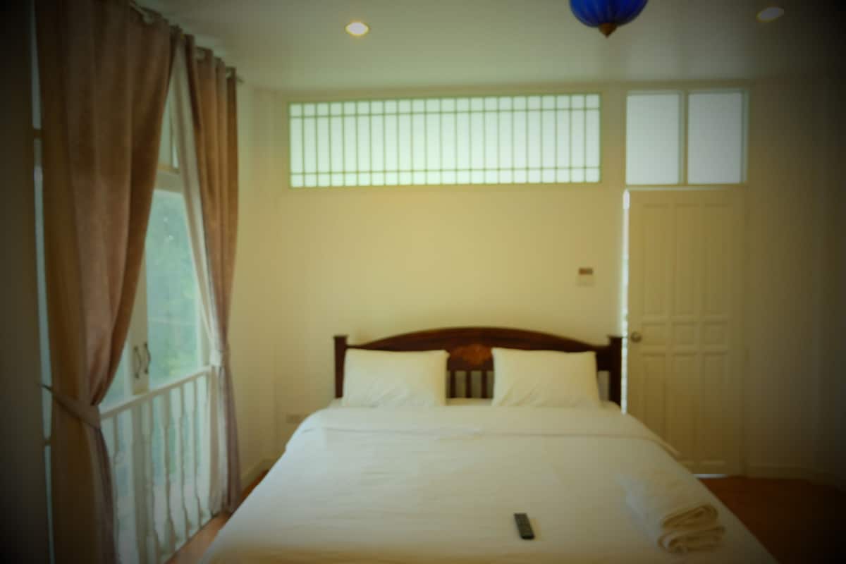 Une chambre à coucher avec un lit, des rideaux, une fenêtre et une porte.