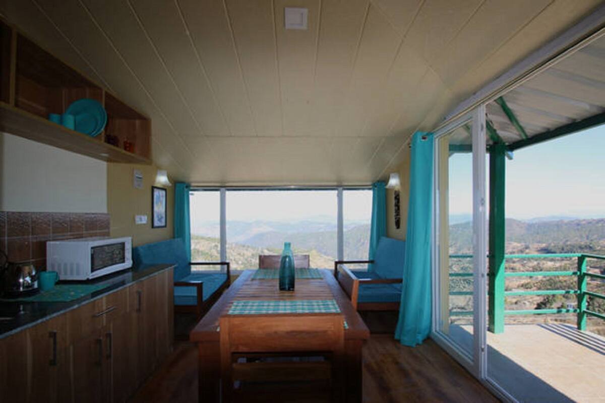 A dining area with a table and chairs, a microwave, and a view of the mountains through large windows.