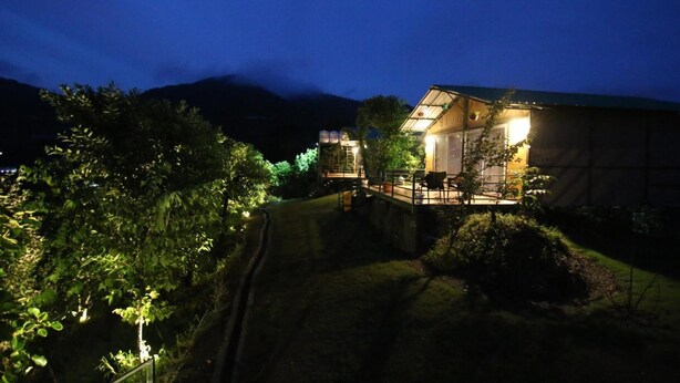 A two-story building with a balcony, surrounded by greenery and hills in the background. - Nest and Hives Mukteshwar (Dhari)