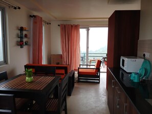 Een compacte keuken met een eethoek, een balkon met een tafel en stoelen, en een magnetron op het aanrecht.
